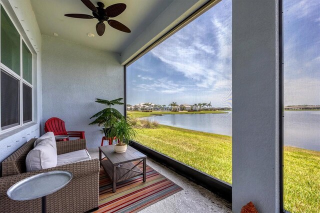 sunroom with ceiling fan and a water view