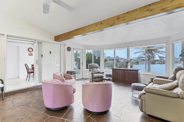 living room with lofted ceiling with beams, ceiling fan, a water view, and a textured ceiling