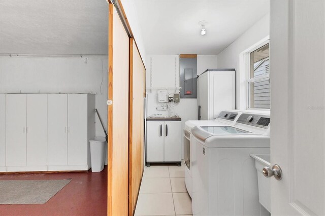 washroom with light tile patterned flooring, washing machine and clothes dryer, and cabinets