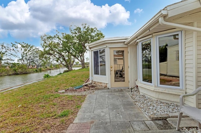 doorway to property featuring a water view, a yard, and a patio