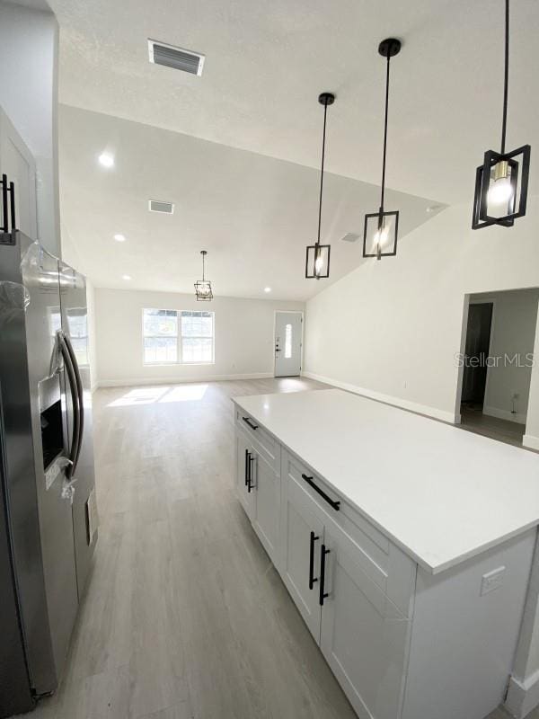 kitchen with white cabinetry, a center island, stainless steel fridge with ice dispenser, decorative light fixtures, and light wood-type flooring