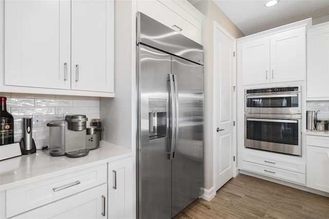 kitchen with stainless steel appliances, white cabinetry, tasteful backsplash, and dark wood-type flooring