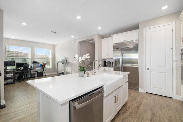 kitchen with a center island with sink, white cabinetry, sink, and appliances with stainless steel finishes