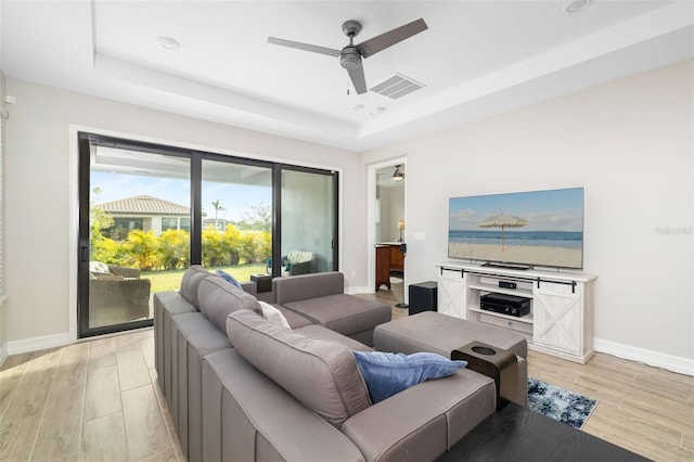 living room featuring a raised ceiling and ceiling fan