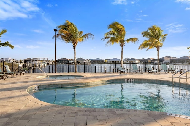 view of swimming pool featuring a hot tub and a patio area