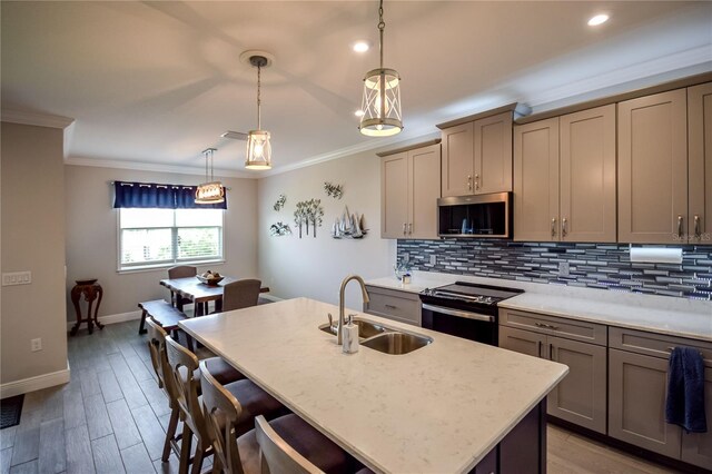 kitchen with sink, hanging light fixtures, ornamental molding, a kitchen island with sink, and black electric range