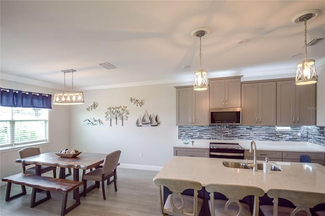 kitchen featuring sink, gray cabinetry, decorative light fixtures, stove, and backsplash