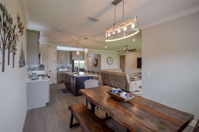 dining room with ceiling fan, ornamental molding, dark hardwood / wood-style flooring, and sink