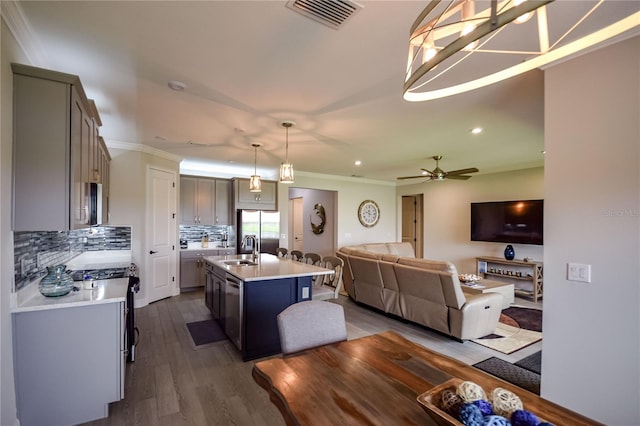 kitchen with sink, pendant lighting, stainless steel appliances, a kitchen island with sink, and decorative backsplash