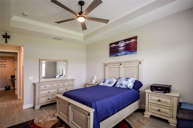 bedroom with ceiling fan, ornamental molding, and a tray ceiling