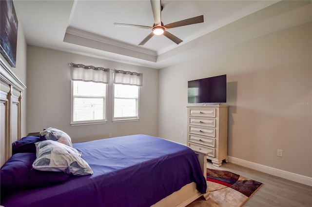 bedroom featuring a tray ceiling, ornamental molding, light hardwood / wood-style floors, and ceiling fan