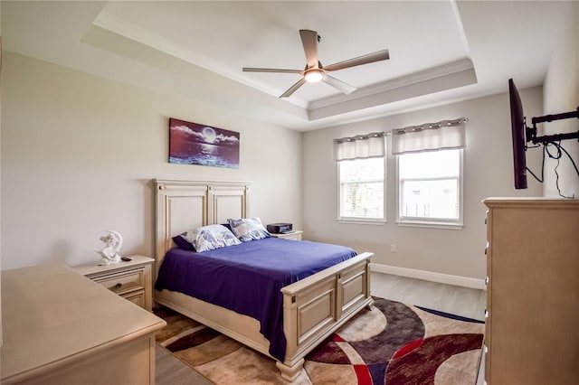 bedroom featuring crown molding, ceiling fan, a raised ceiling, and light hardwood / wood-style flooring