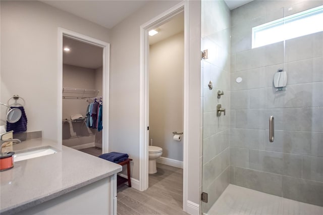 bathroom with walk in shower, wood-type flooring, vanity, and toilet