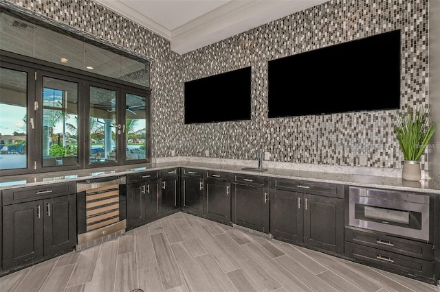 bar with crown molding, oven, beverage cooler, light stone countertops, and decorative backsplash