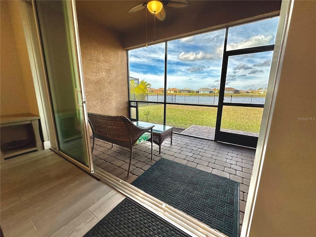 unfurnished sunroom featuring a water view and ceiling fan