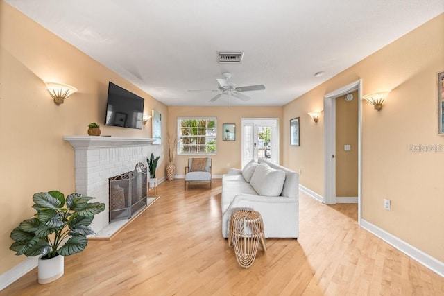 living room featuring a fireplace, french doors, light hardwood / wood-style floors, and ceiling fan