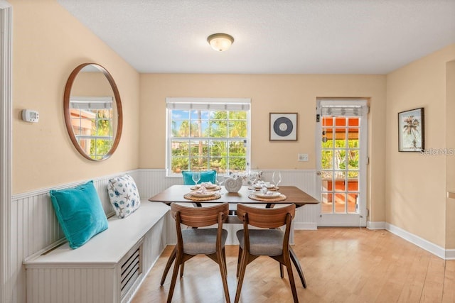 dining area featuring breakfast area, a textured ceiling, and light hardwood / wood-style flooring