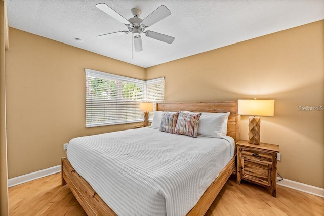 bedroom with ceiling fan, hardwood / wood-style floors, and a textured ceiling