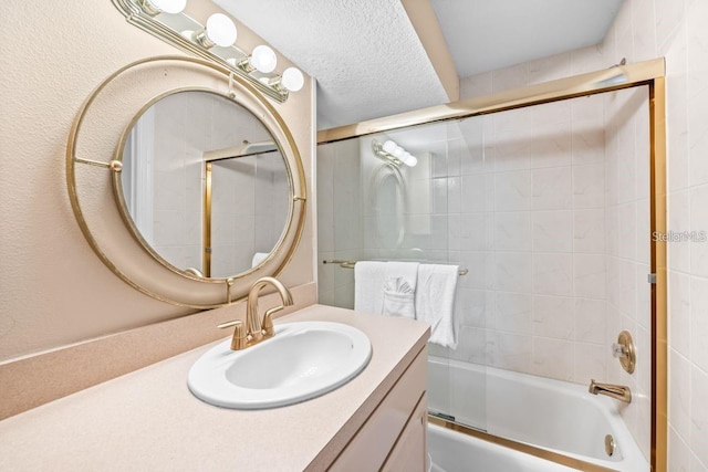 bathroom with vanity, a textured ceiling, and combined bath / shower with glass door