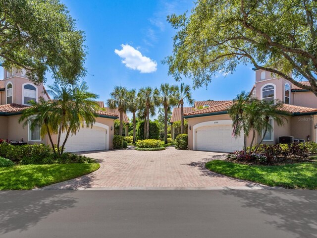 mediterranean / spanish-style home with a garage and central air condition unit