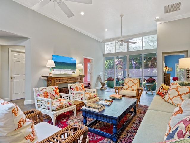 living room with tile patterned flooring, ceiling fan, a towering ceiling, and ornamental molding