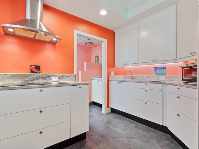 kitchen featuring black electric cooktop, white cabinetry, and range hood