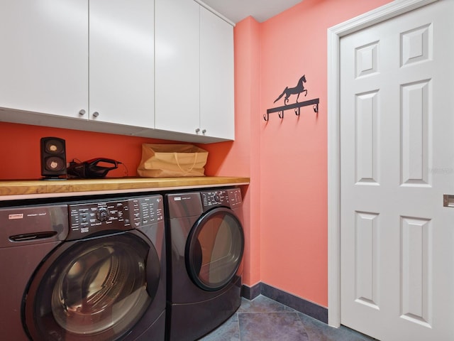 washroom with cabinets, washing machine and dryer, and dark tile patterned flooring