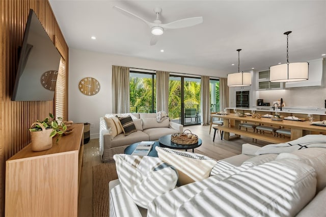 living room with light hardwood / wood-style floors, ceiling fan, and sink