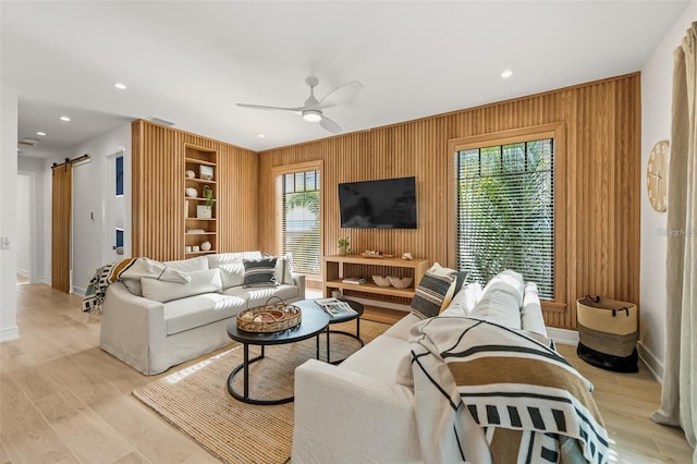 living room featuring a barn door, ceiling fan, plenty of natural light, and built in features