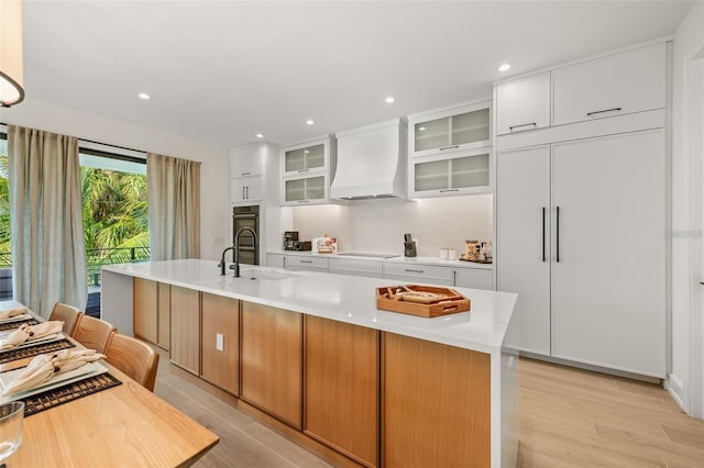 kitchen featuring custom range hood, a spacious island, sink, electric cooktop, and white cabinets