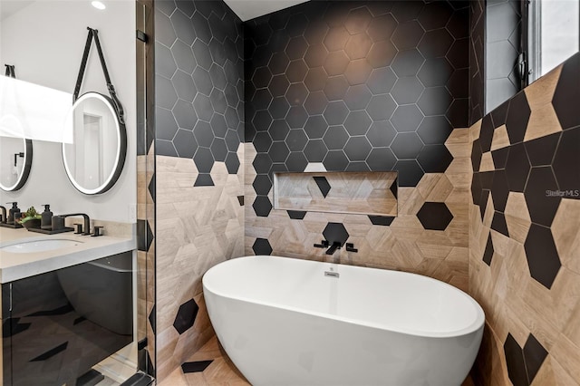 bathroom featuring a bathing tub, vanity, tile walls, and tile patterned flooring