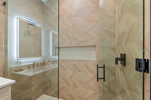 bathroom featuring a shower with door and vanity