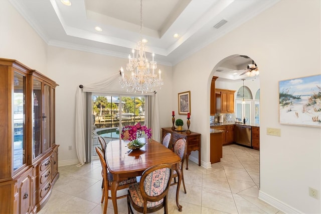 dining space featuring a tray ceiling, light tile patterned flooring, ceiling fan with notable chandelier, and ornamental molding