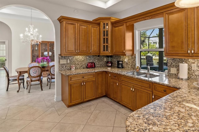 kitchen featuring sink, tasteful backsplash, a notable chandelier, decorative light fixtures, and light tile patterned floors