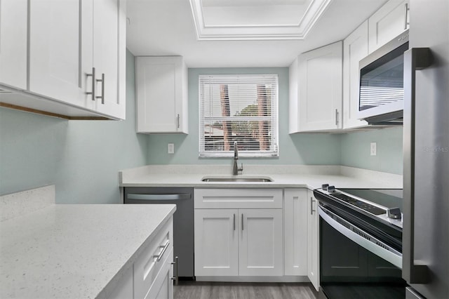 kitchen featuring sink, light stone counters, light hardwood / wood-style floors, white cabinets, and appliances with stainless steel finishes