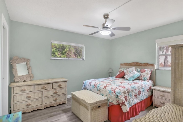 bedroom featuring ceiling fan, light wood-type flooring, and multiple windows