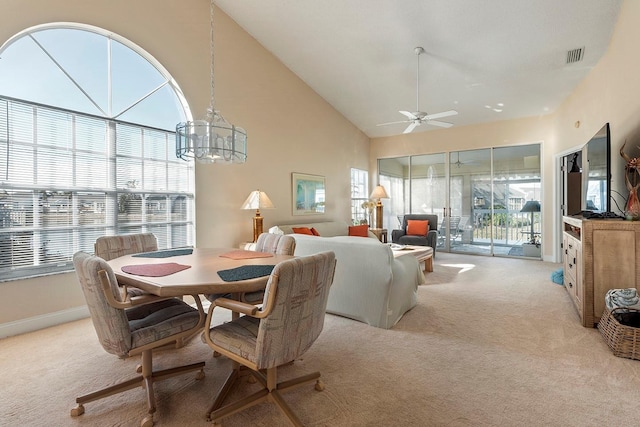 dining room with light carpet, ceiling fan with notable chandelier, and high vaulted ceiling