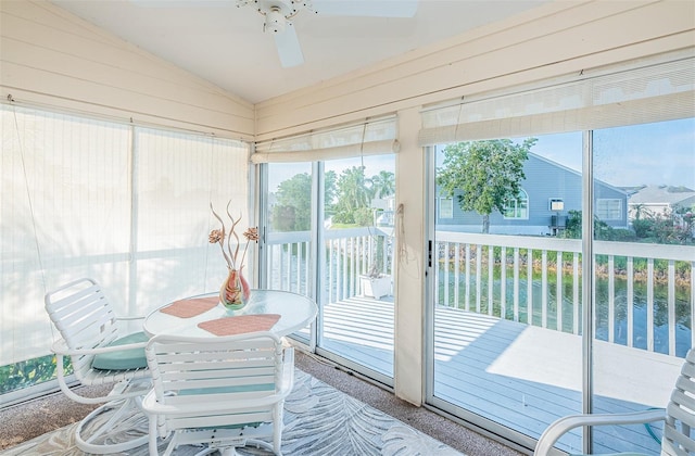 sunroom / solarium featuring ceiling fan, a water view, and vaulted ceiling