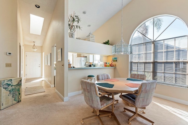 carpeted dining room featuring a skylight, high vaulted ceiling, and sink