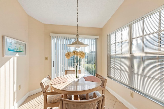 dining space with light tile patterned floors, a textured ceiling, and vaulted ceiling