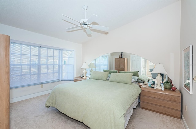 bedroom with multiple windows, light colored carpet, vaulted ceiling, and ceiling fan