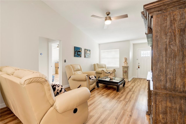 living room with ceiling fan, light hardwood / wood-style floors, and vaulted ceiling