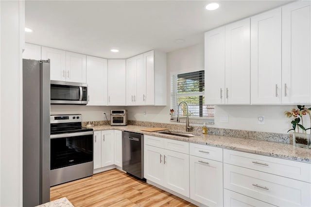 kitchen with light wood-type flooring, stainless steel appliances, white cabinetry, and sink