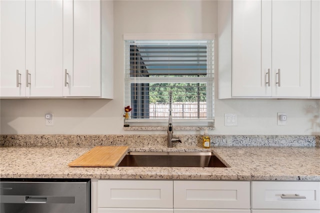 kitchen with white cabinets, dishwasher, light stone counters, and sink