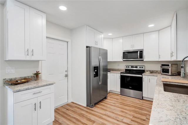 kitchen with white cabinets, stainless steel appliances, light hardwood / wood-style floors, and sink