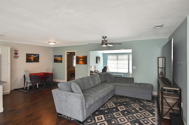 living room with a textured ceiling, dark hardwood / wood-style flooring, and ceiling fan