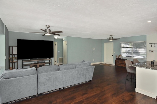 living room with ceiling fan, dark wood-type flooring, and a textured ceiling