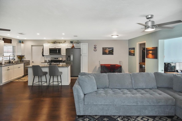 living room with ceiling fan, dark wood-type flooring, and sink