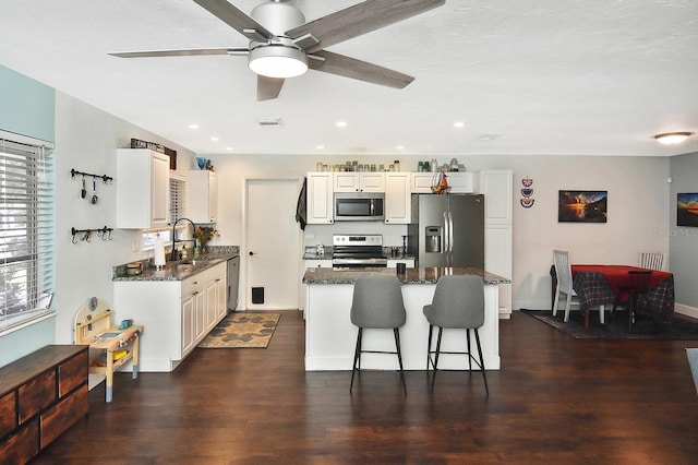 kitchen featuring a kitchen breakfast bar, sink, ceiling fan, dark hardwood / wood-style flooring, and stainless steel appliances