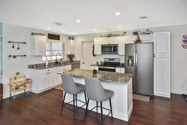 kitchen featuring dark hardwood / wood-style floors, a center island, white cabinetry, and stainless steel appliances